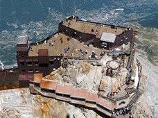 Vue plongeante sur une station d’altitude accrochée à la roche, au-dessus de la vallée.