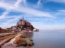 Le Mont-Saint-Michel sous un ciel bleu, la mer à marée haute.